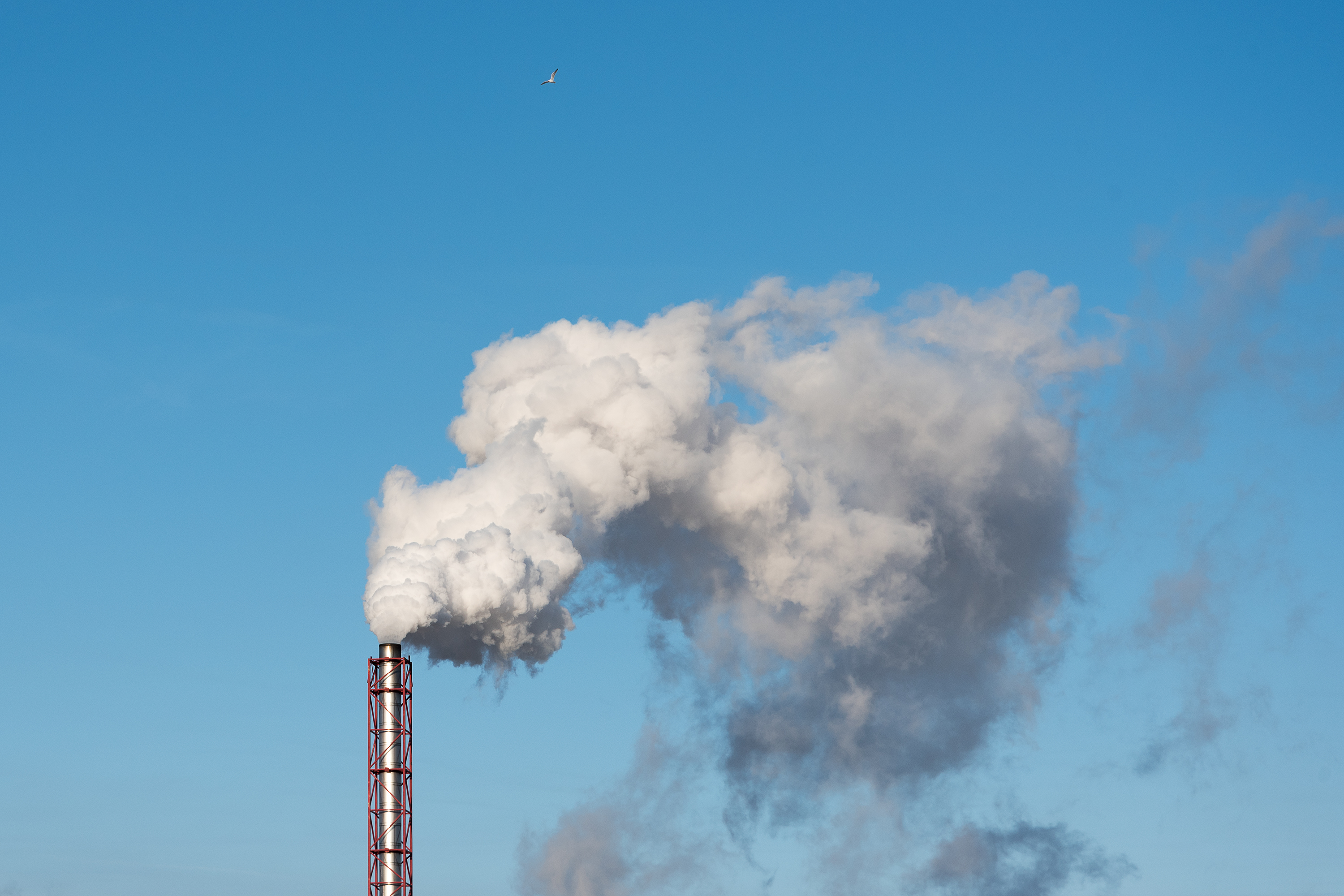 Chimney and smoke against blue sky.